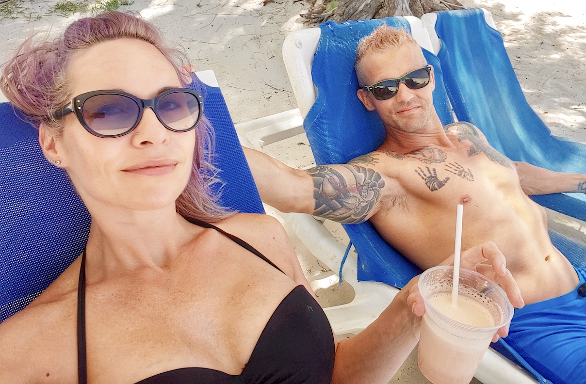 couple on lounge chairs in the shade on the beach